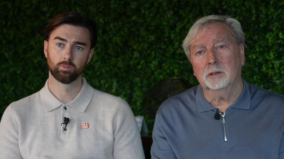 Charlie and Steve Sheen in smart jumpers with microphones pinned to them for the interview