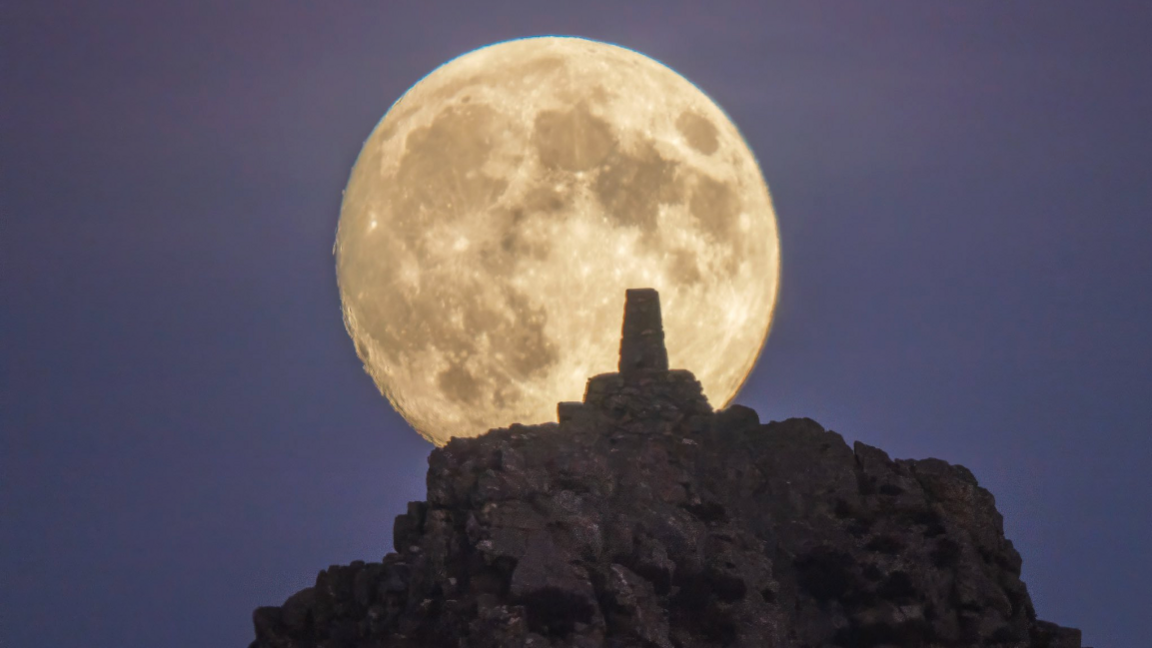 The supermoon rising behind Manstone Rock on The Stiperstones in Shropshire