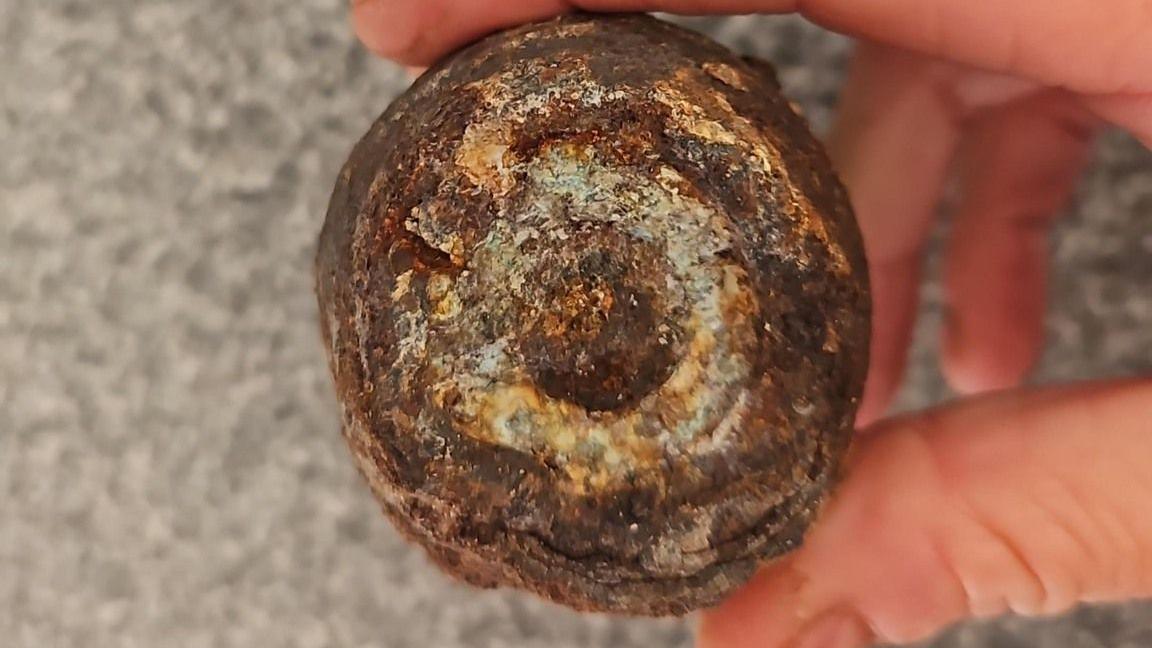 A rusted object being held in a person's hand.