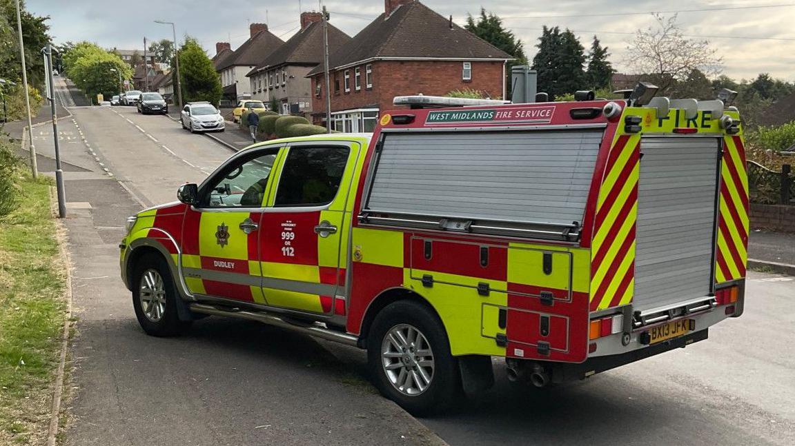 A fire service vehicle parked on the road and pavement on a residential road