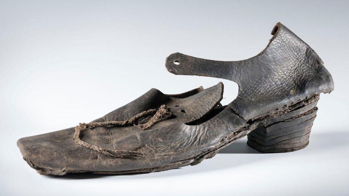 A 17th Century leather shoe with a square toe, a small heel and the remains of a leather lace recovered from the London wreck