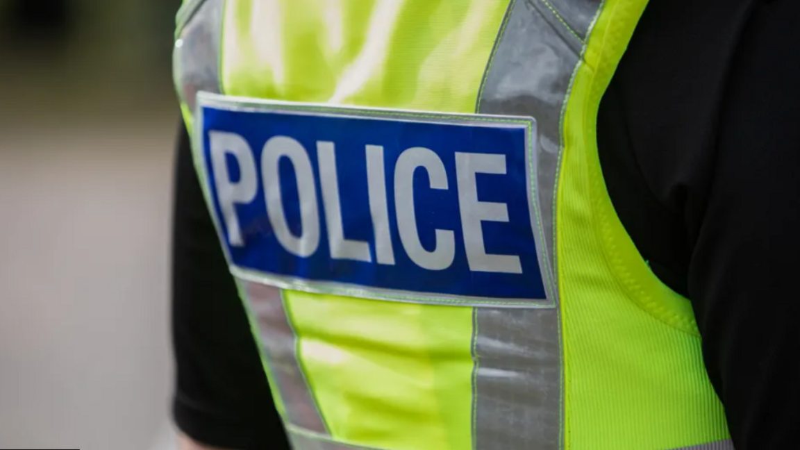 A bright green police vest with the word "Police" in white bold letters and a blue background