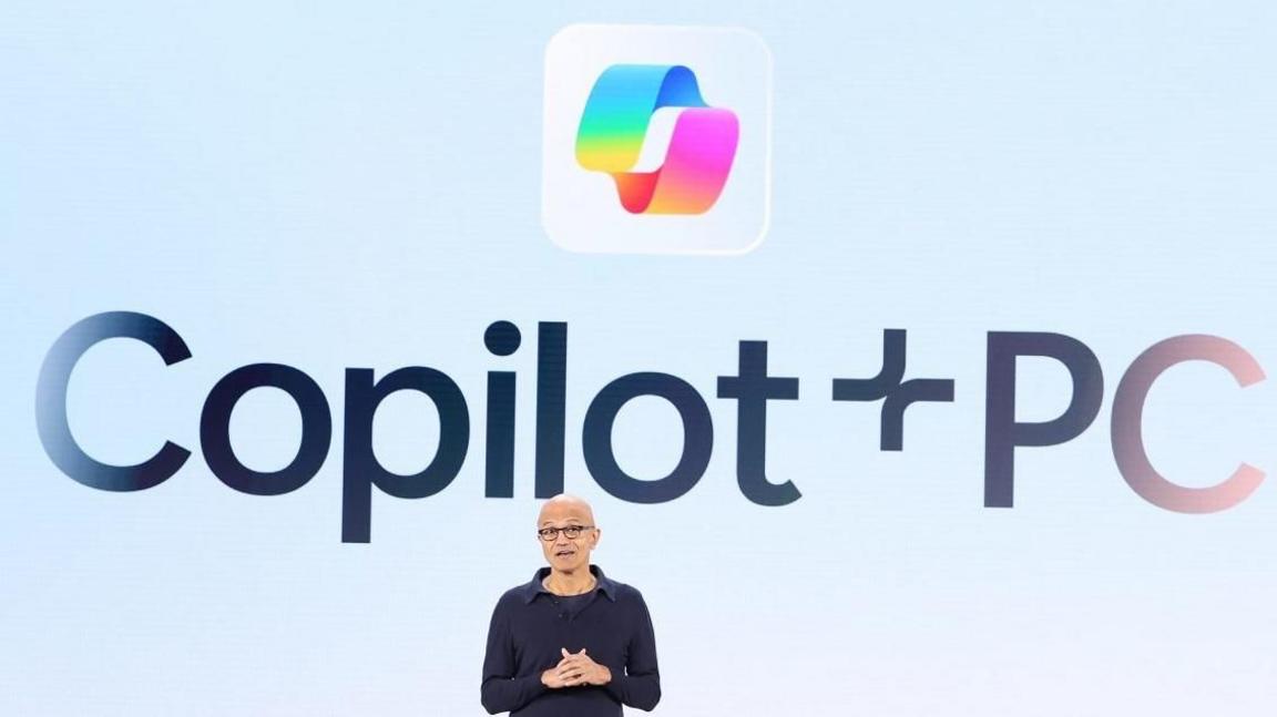 Satya Nadella on stage in front of a large Copilot+ logo