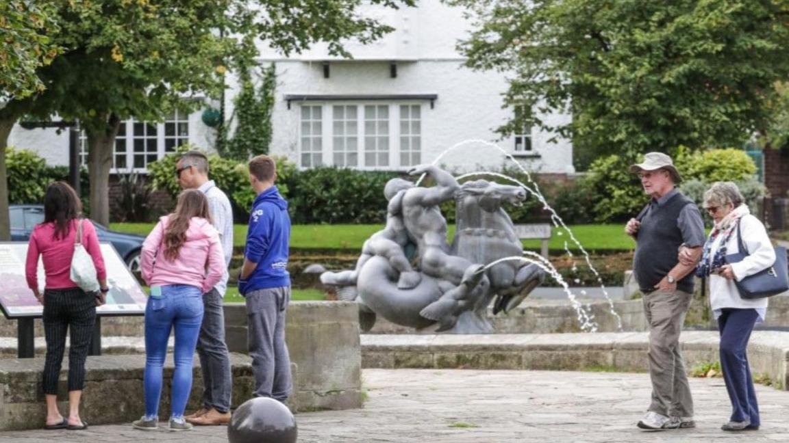 People stand by the pond and fountain when it flowed