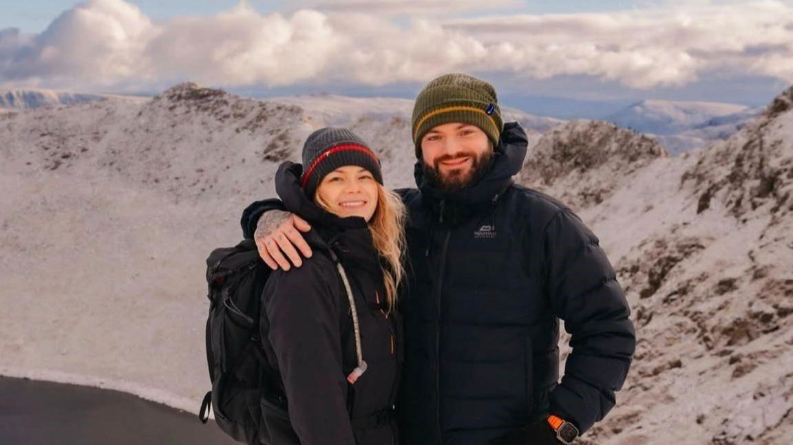 Damon Alexander-Cole, is pictured here with his partner Kirsty Doyle, on a mountain rain on a sunny day