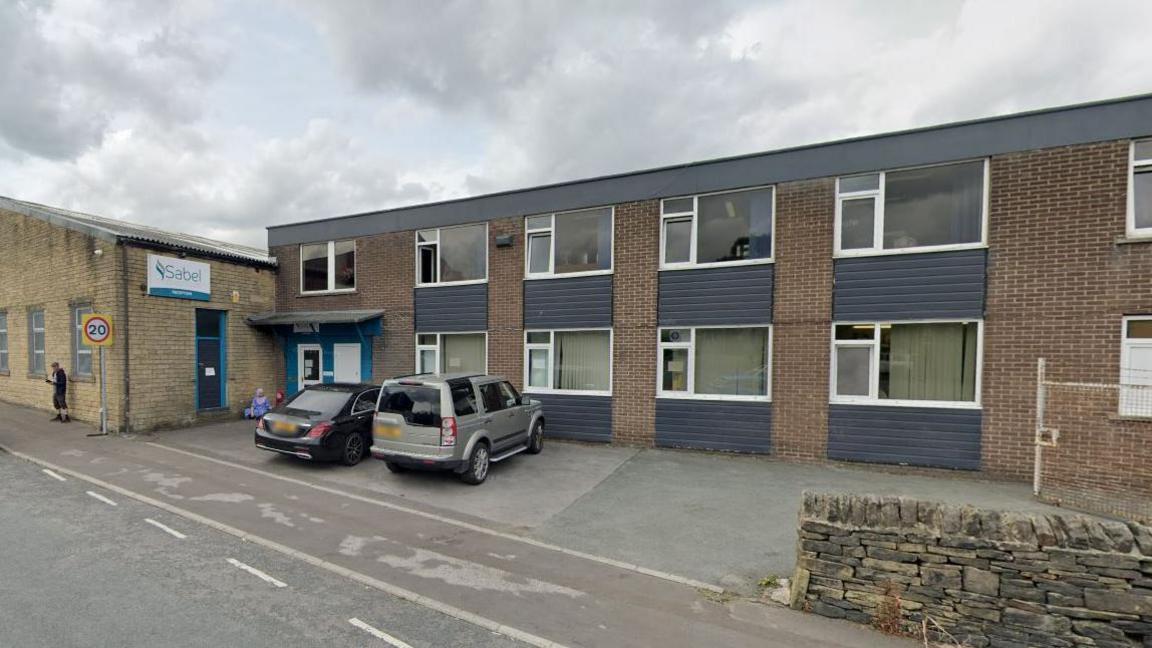 An office in Halifax, West Yorkshire, with cars parked in bays outside a two-storey building with a flat roof. An adjoining building has a company sign reading "Sabel".
