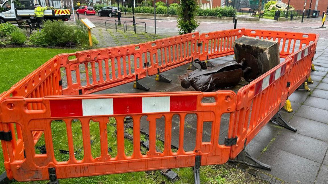 Orange barriers surround the statue of Victoria Wood