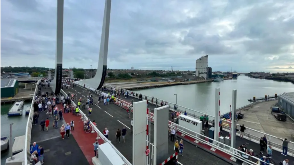 An aerial view of Gull Wing Bridge in Lowestoft. There are people walking across the bridge, with a view to the right of Lake Lothing.