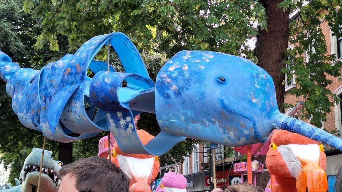 A close up of a giant blue Narwal puppet