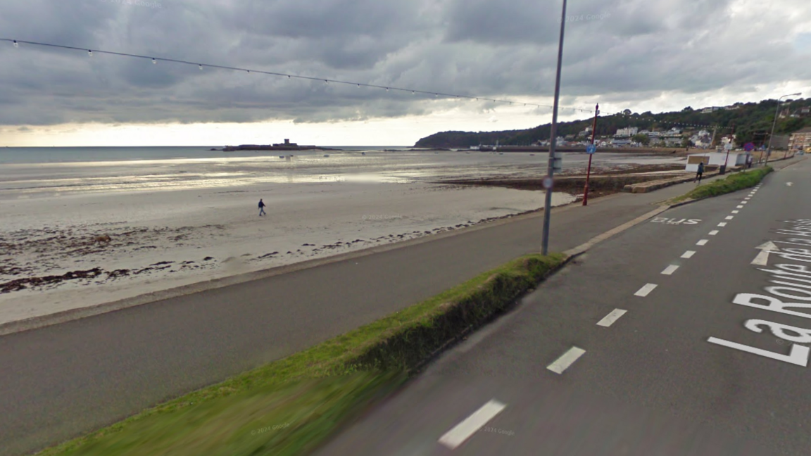 The sea wall at La Haule. The sea can be seen, with a lowered wall and a road to the right of it.