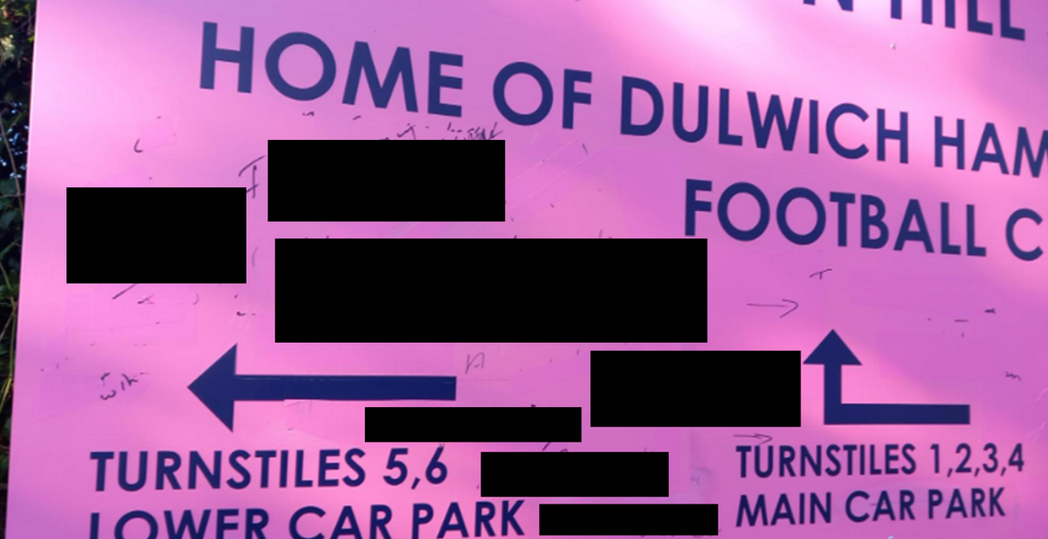 A pink Dulwich Hamlet FC sign with black blocks showing where offensive comments had been written