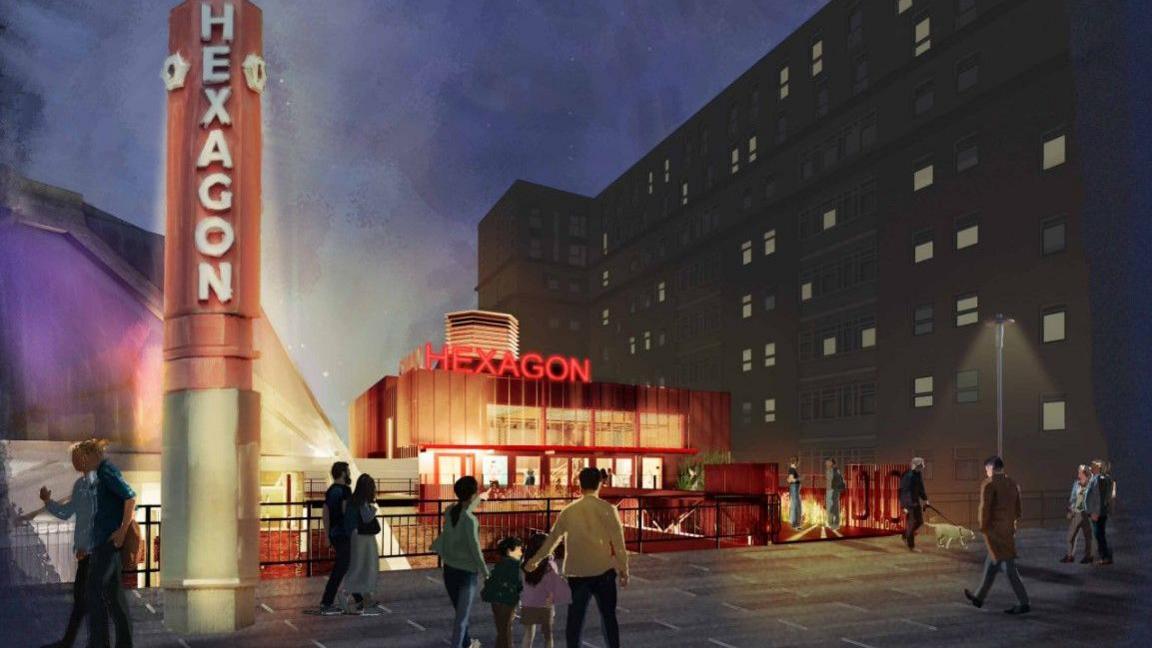 A computer generated image of the outside of  the theatre. It's a blocky red building with "Hexagon" written over the doors. There's a pillar next to it, lit up in red, that also has the word "Hexagon" written on it.