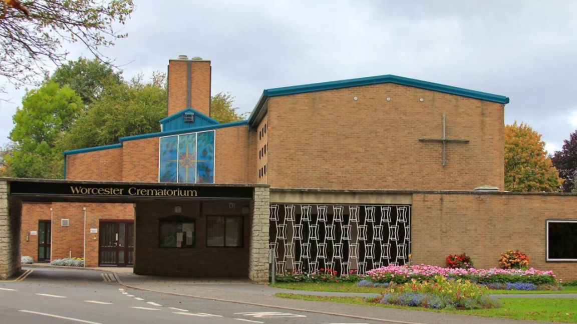 A two storey building that has the sign 'Worcester crematorium' in gold writing on a black background