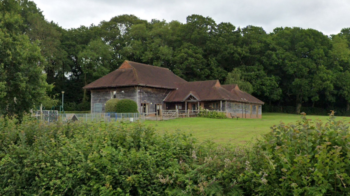 A Google Street image of the dark wood and red brick village hall.