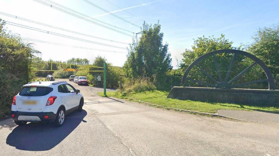 An image of a white car driving into the car park entrance of Poolsbrook Country Park in Chesterfield.