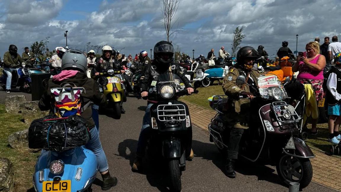 A gathering of scores of scooters and riders