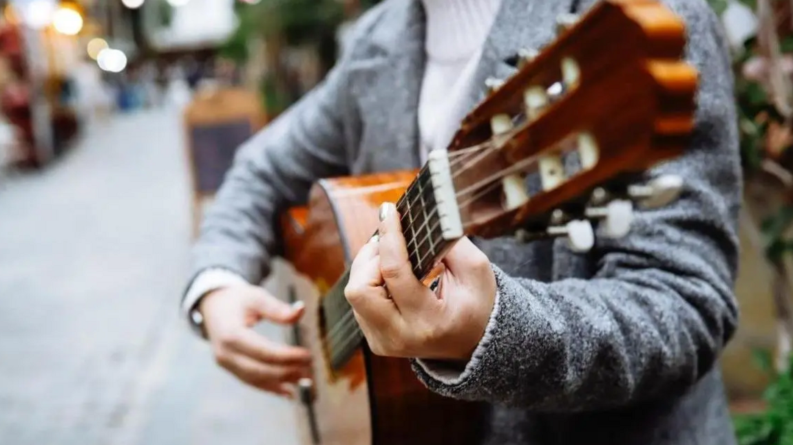 A stock image of a man playing a guitar on a street.
