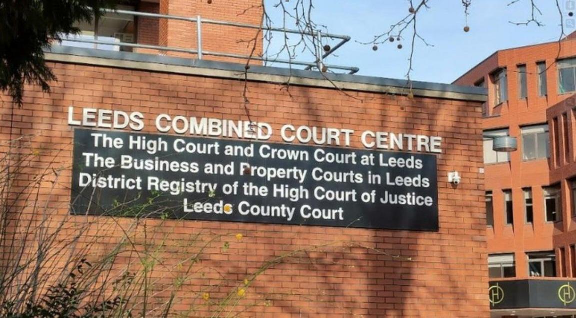 The outside of Leeds Crown Court - a redbrick building featuring a sign reading "Leeds Combined Court Centre: The High Court and Crown Court at Leeds; The Business and Property Courts in Leeds; District Registry of the High Court of Justice; Leeds County Court".