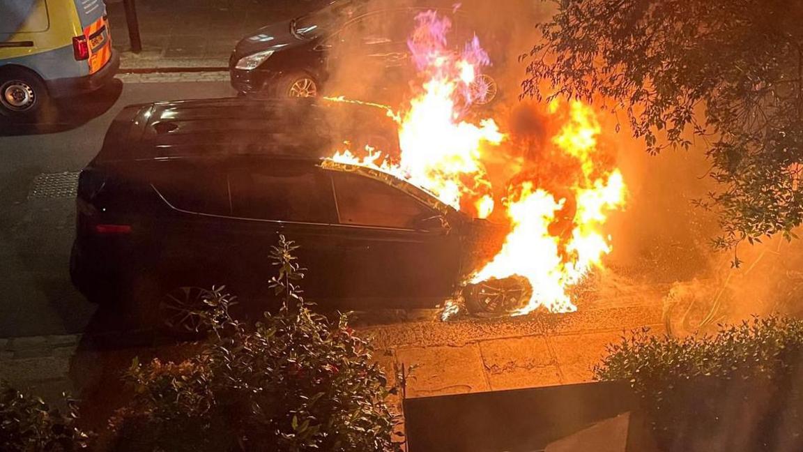 A car on fire during the night.