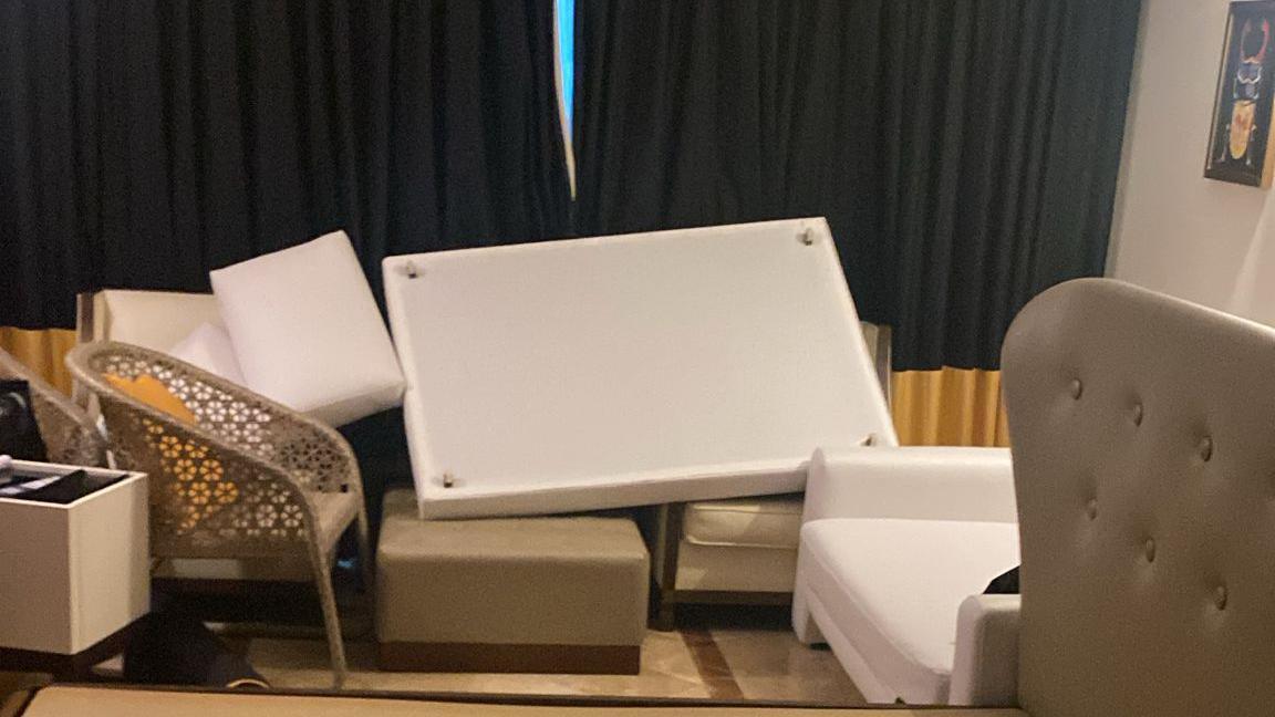 A close up of the furniture barricading the windows. There is a bed and chairs propped up against the glass while the curtains are closed.