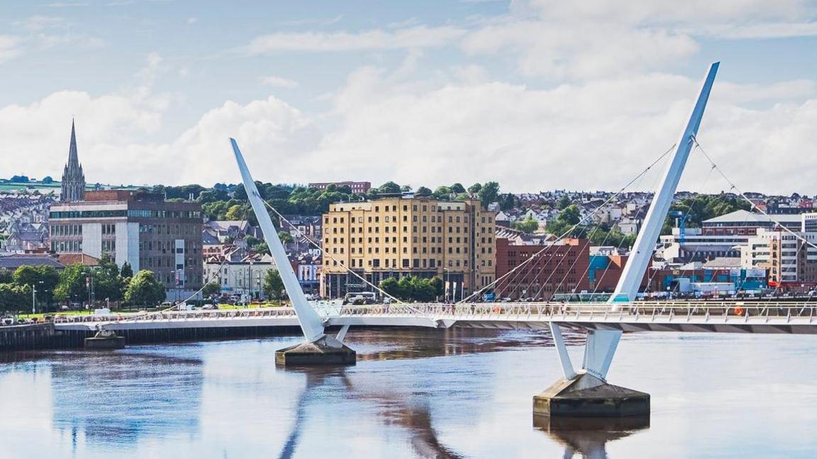 The Peace bridge spanning the river foyle with a view of the cityside, including the guildhall and city hotel.