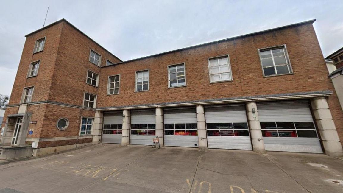 A 1950s brick-built fire station with four bays for fire engines and metal-framed windows.