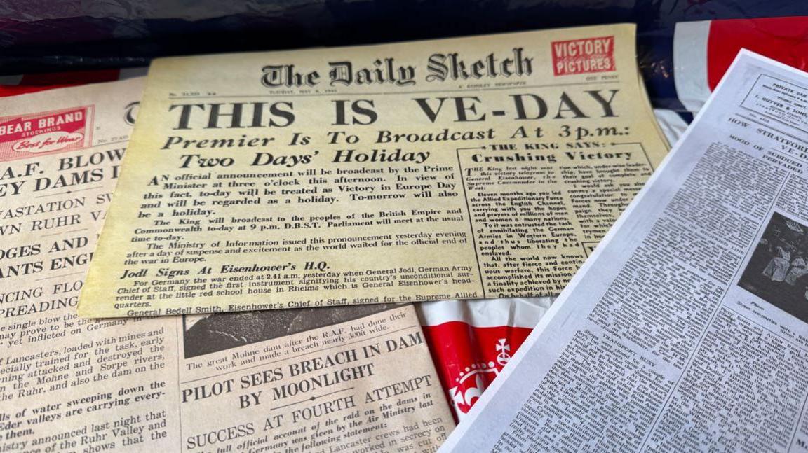 A collection of newspapers and items from VE day.