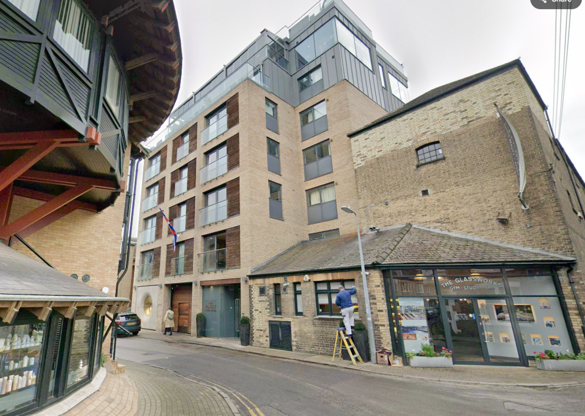 The Varsity Hotel and Spa - a modern, light-coloured brick building with about seven storeys. It is on a narrow street. There is a shop of the corner of the street, attached to the hotel building.
