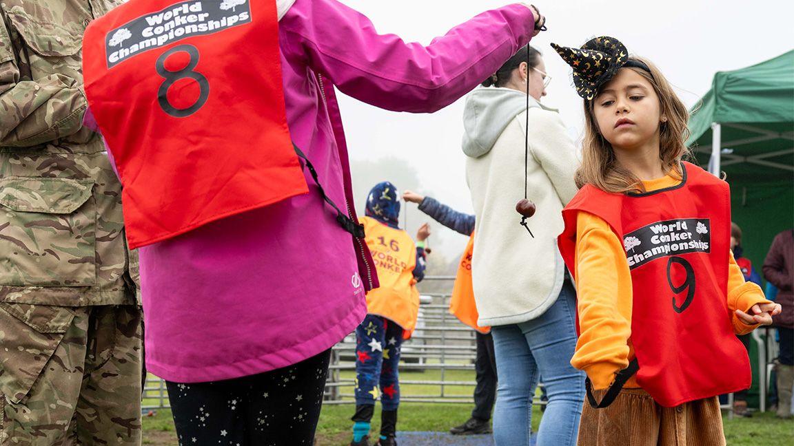 Two girls play conkers.