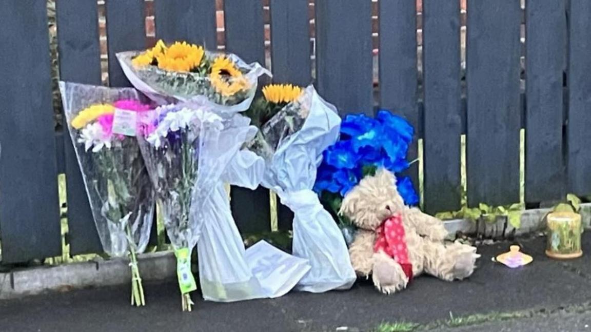 Floral tributes and a teddy bear left outside a house