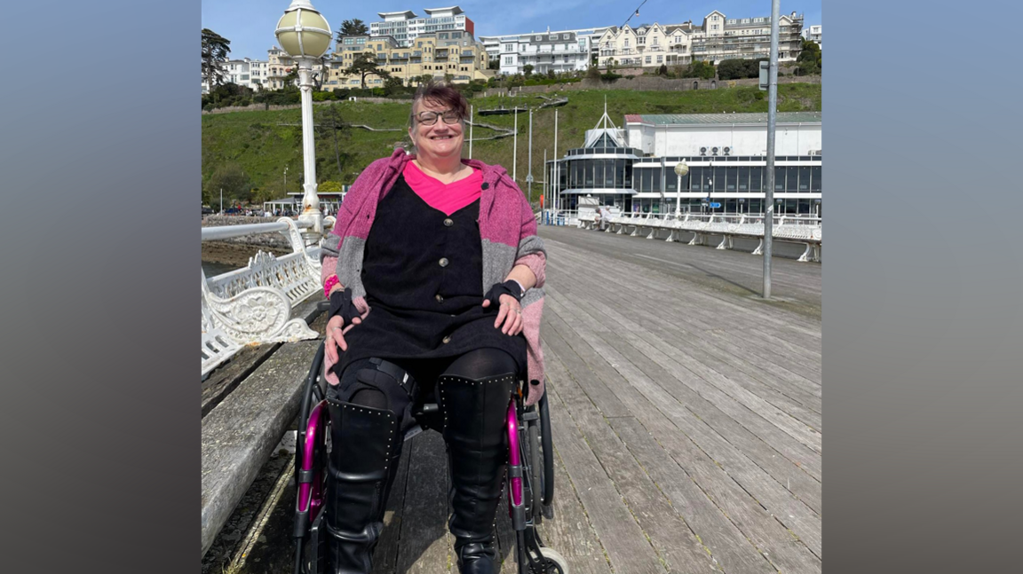 Dr Ali Carre in a wheelchair smiles at the camera on a pier