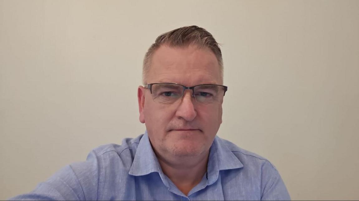 Michael Brady, with grey hair, glasses and blue jacket, looking at the camera.