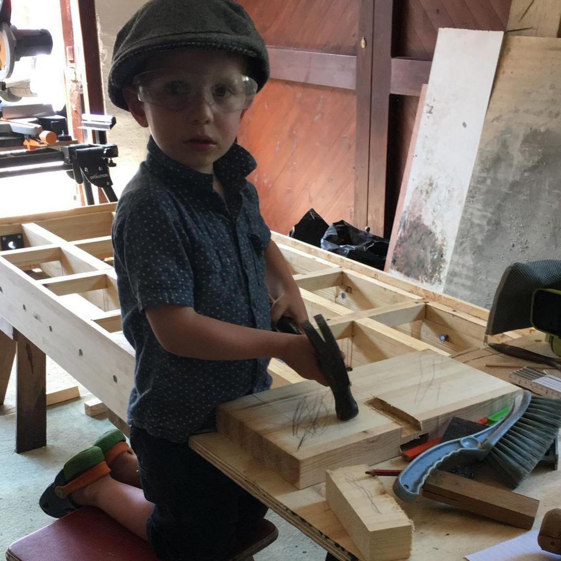 Alfie, aged four, with a toy drill in a workshop.