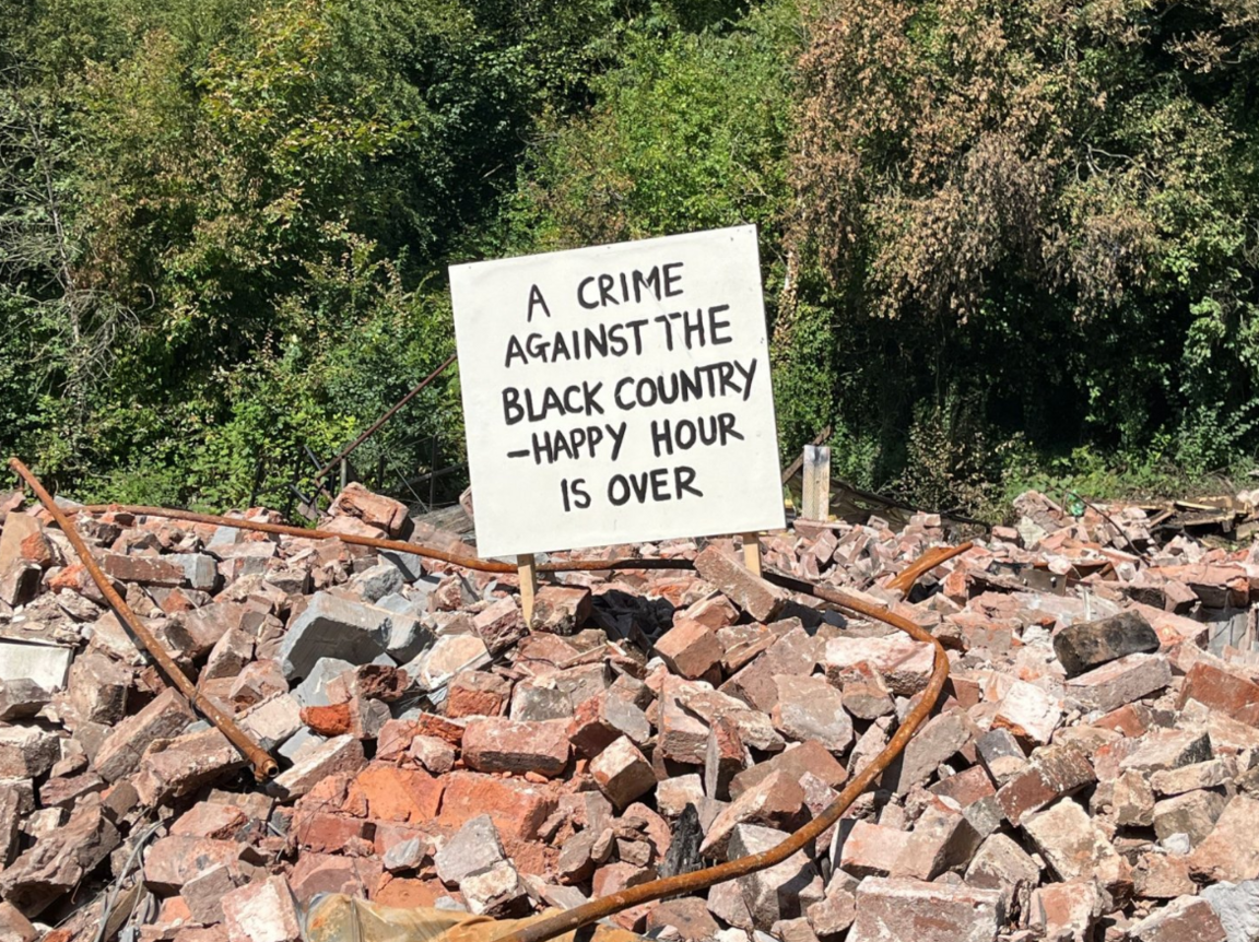 A protest sign lodged in the rubble of the Crooked House