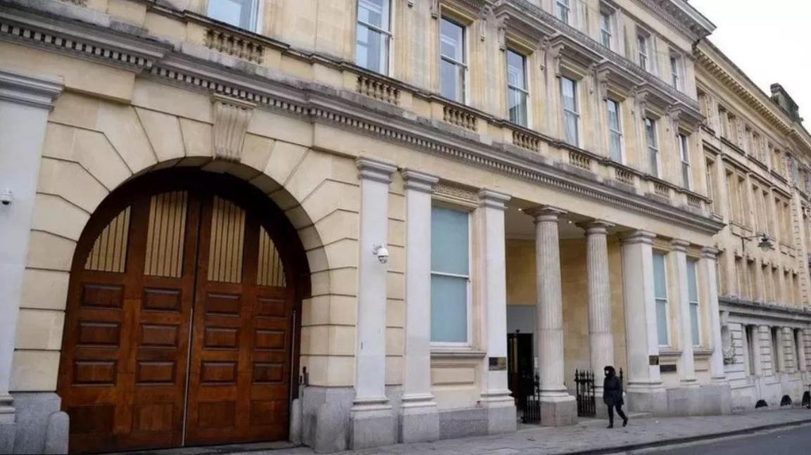 The exterior of Bristol Crown Court. It is a large sandstone coloured building with pillars outside and a large rounded wooden door on the left 