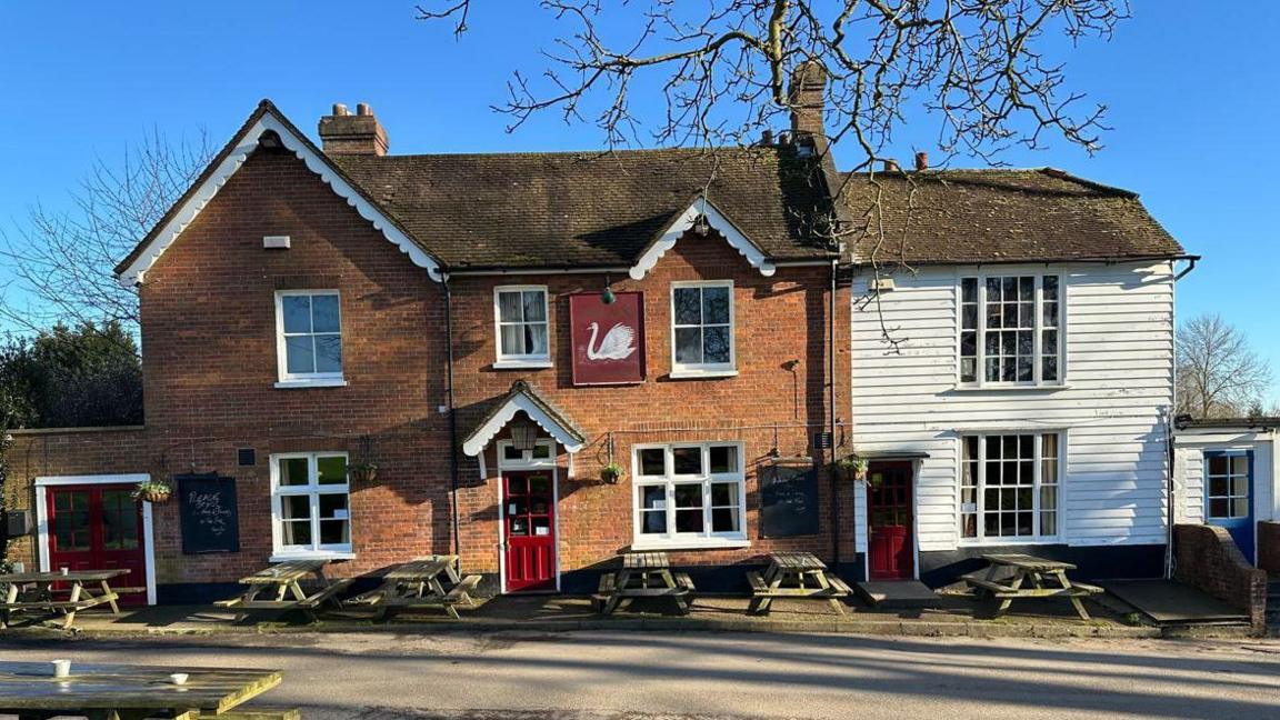 An exterior shot of front of the Swan on the Green pub in West Peckham - a partly brown brick and white panelled building