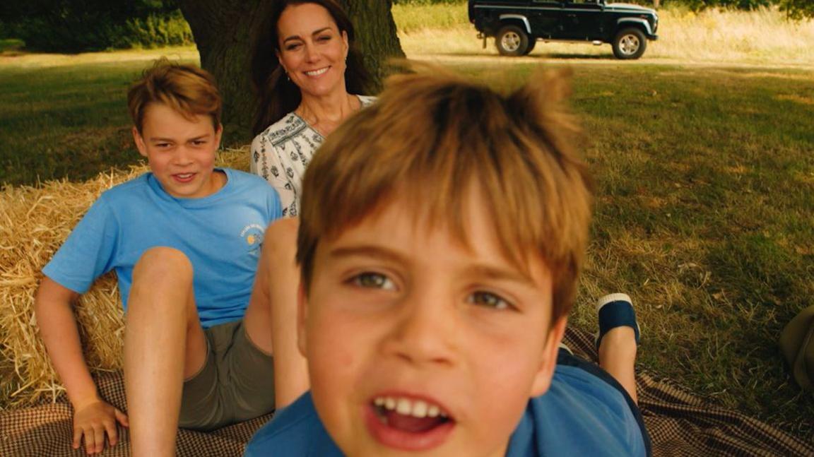 Princes Louis and George play in front of the camera while their mother Catherine looks on with an amused face