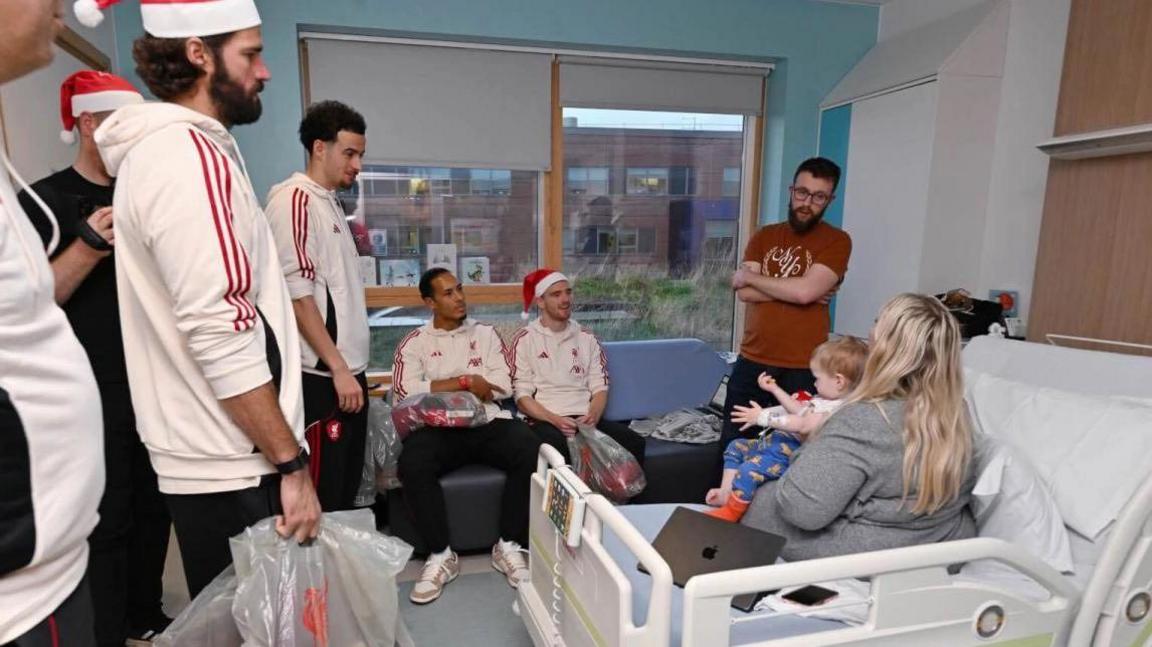 Chwaraewyr Lerpwl a'r rheolwr Arne Slot yn dosbarthu anrhegion i Ffredi yn ystod ymweliad eleni. 