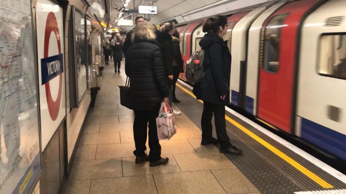 People waiting on Tube platform to get on a Victoria line train 