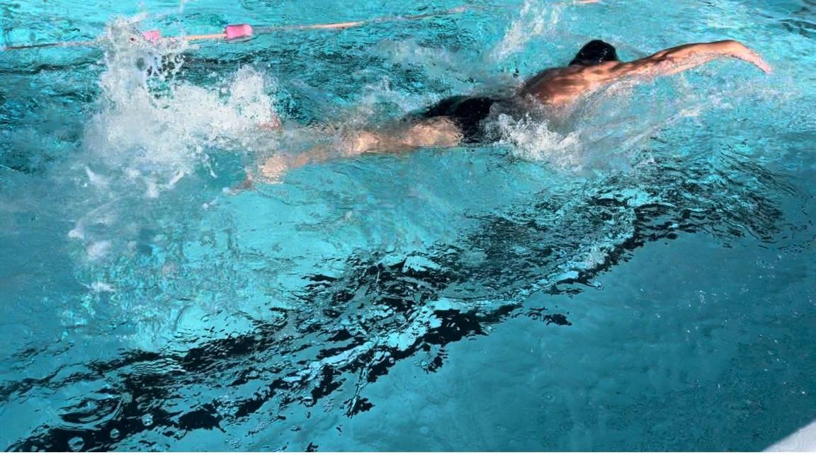 Man swimming front crawl in a public pool