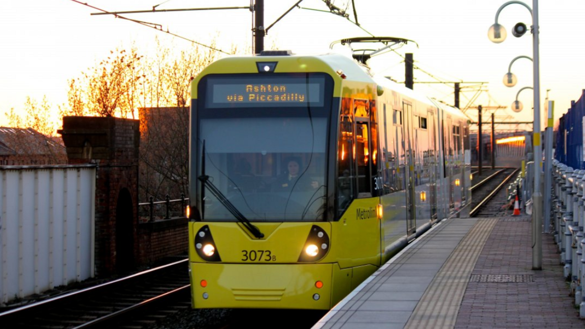 A yellow Metrolink tram arrives at a station