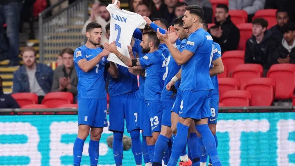 Greece's national team hold George Baldock's shirt aloft in his memory