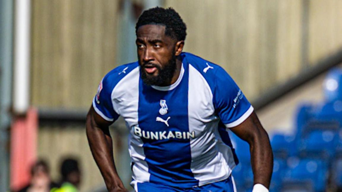 Manny Monthe looks to his right while running in a blue and white shirt