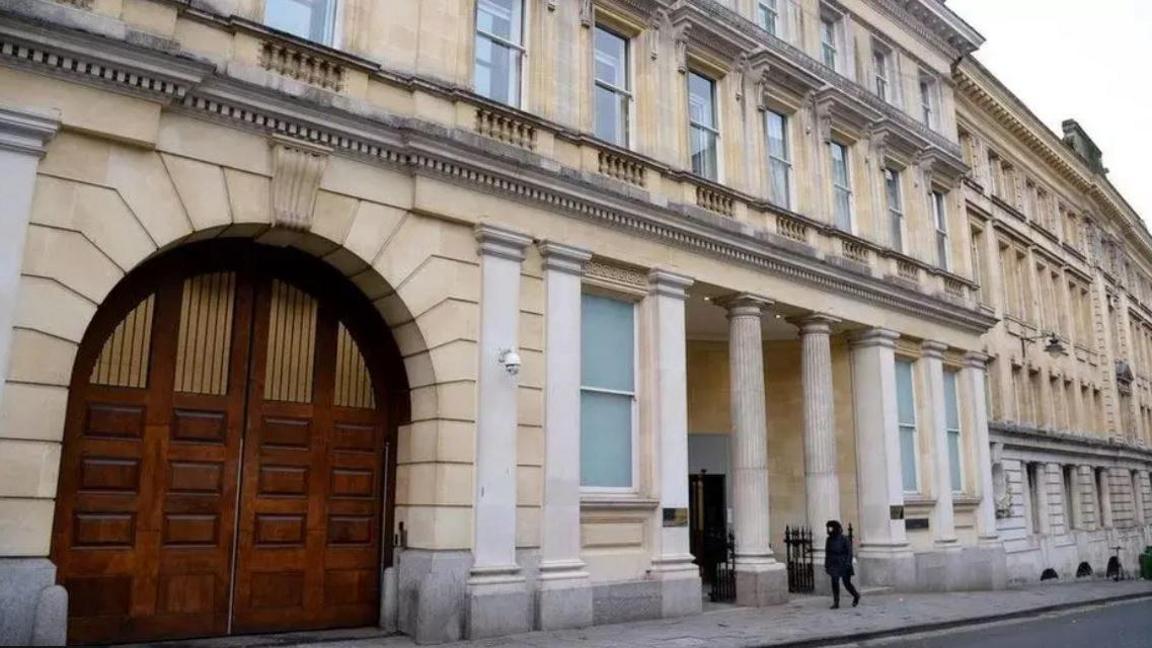 The exterior of Bristol Crown Court. It is a large sand coloured building with pillars outside the entrance, and a large rounded wooden door on the left. 