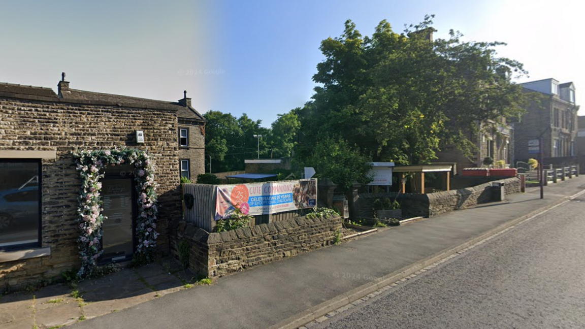 A building behind a low Yorkshire stone wall. A sign reading Cute Companions is placed across the wall. A large tree is on one side of the wall.