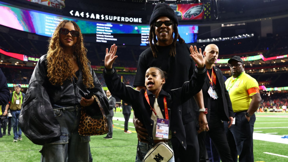 Blue Ivy wears an oversized leather jacket paired with casual cargo denim; while standing next to her father Jay Z and sister Rumi

