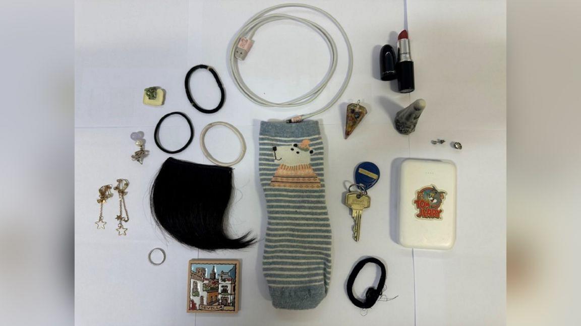 A collection of random items on a table, including jewellery and clothing.