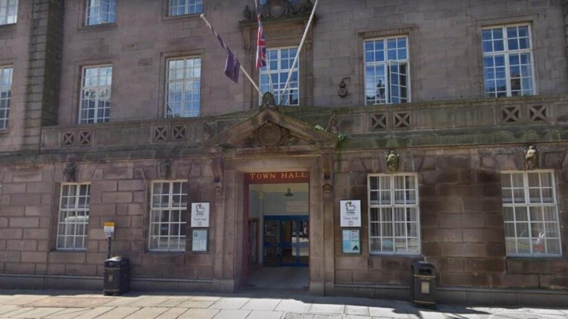 An exterior shot of Preston Town Hall shows the entrance, two windows on either side of it and flags including the Union flag flying above it