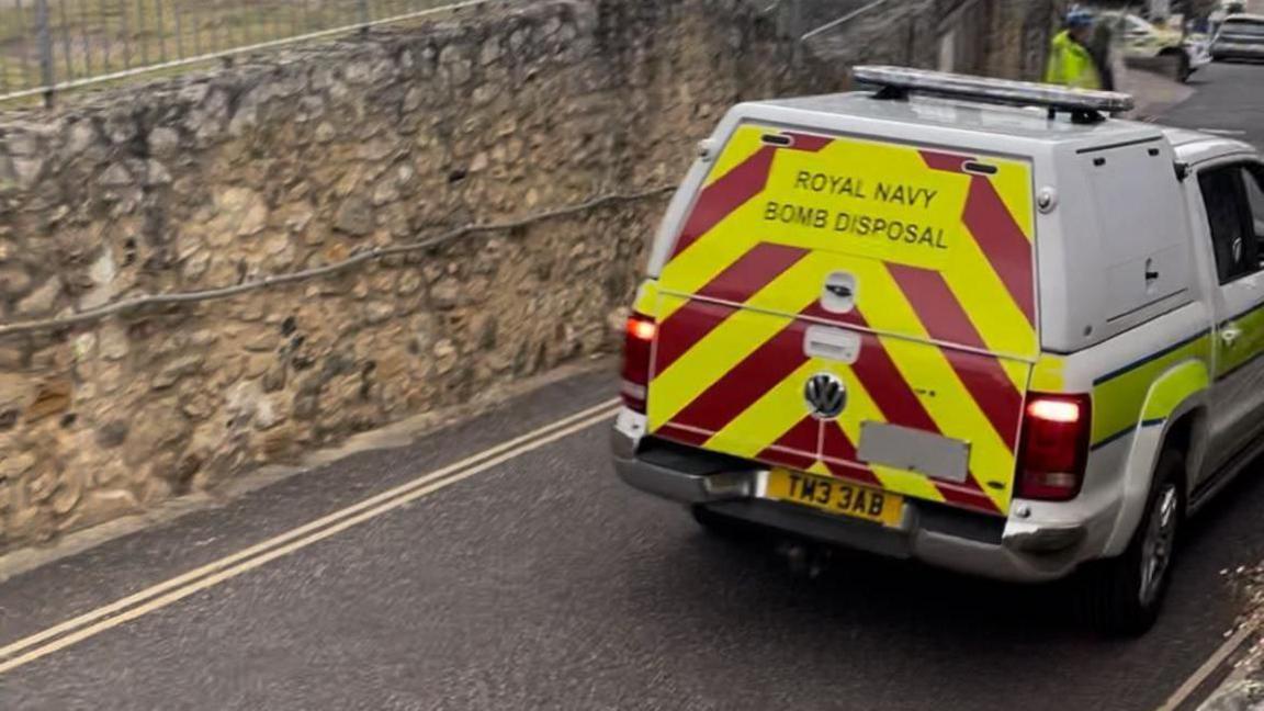 A white Royal Navy Bomb Disposal unit vehicle driving down a road towards Beer beach