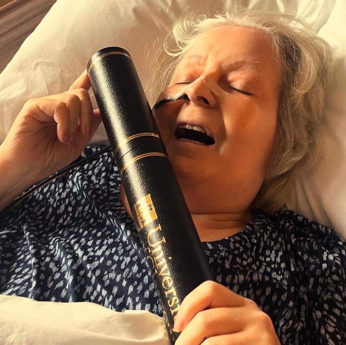 Janey Godley holding a black tube with the University of Glasgow logo on it